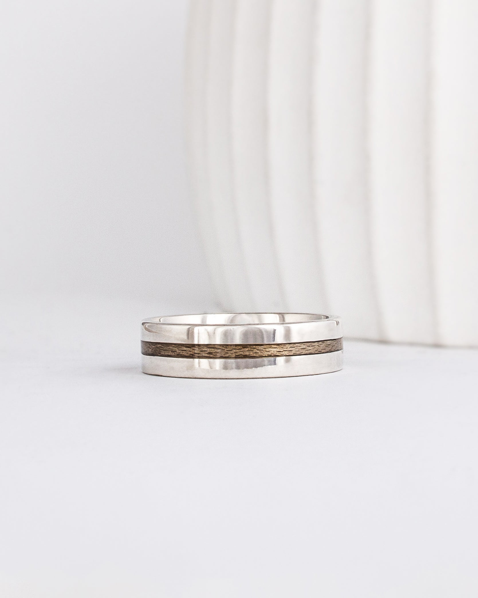 a modern wooden wedding ring for men or women featuring white gold, a flat profile and a central inlay of greyed Maplewood