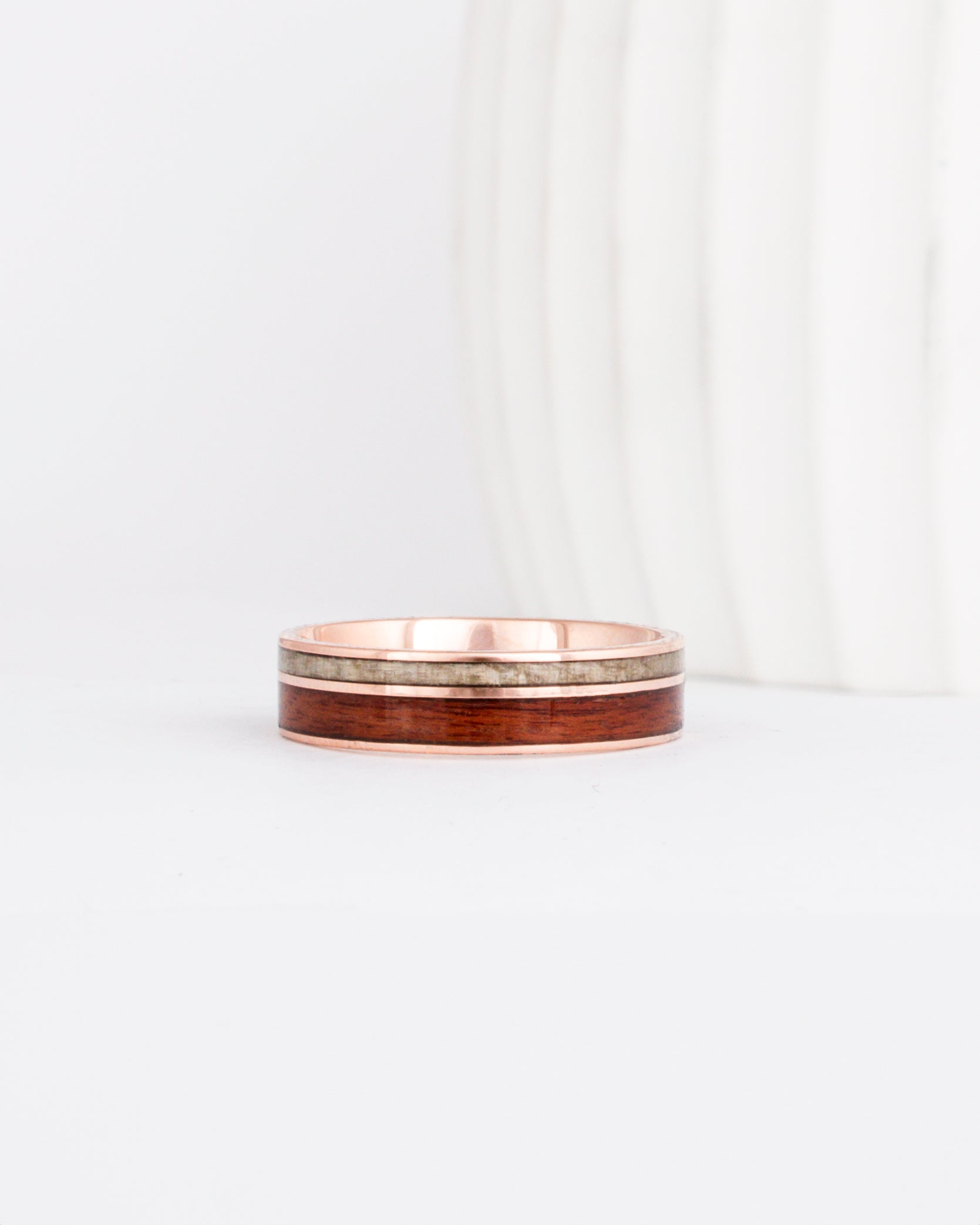 a rose gold wooden wedding ring featuring two wood inlays in complimentary colors.